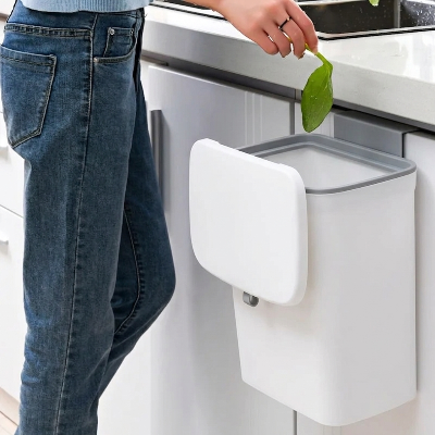 Personne qui dépose déchets dans poubelle cuisine sous évier