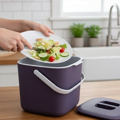 Dépôt restes alimentaires depuis assiette dans poubelle cuisine violette