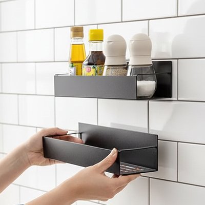 Personne collant une étagères à épices au mur de tuile