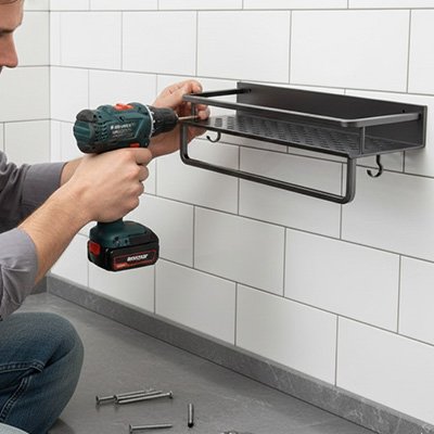 Personne installant au mur l'étagère à épices 