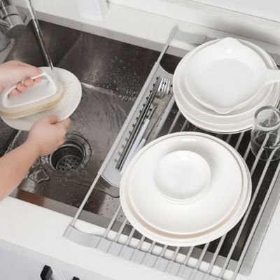 Personne rinçant assiette à côté Égouttoir vaisselle inox